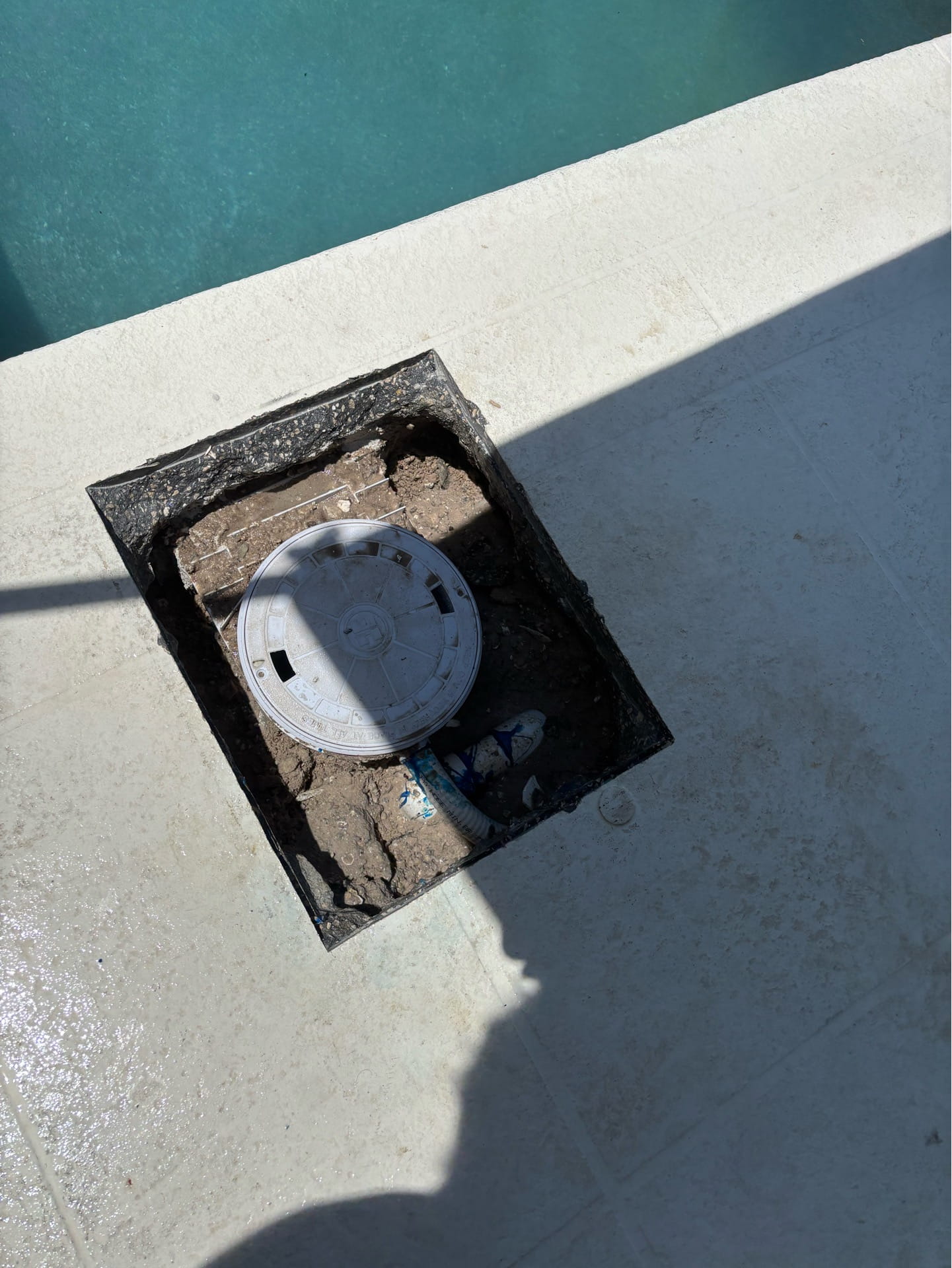 A damaged pool skimmer opened up on the deck for replacement.