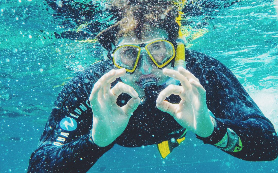 Diver performing pool leak detection on PebbleTec pool surface.